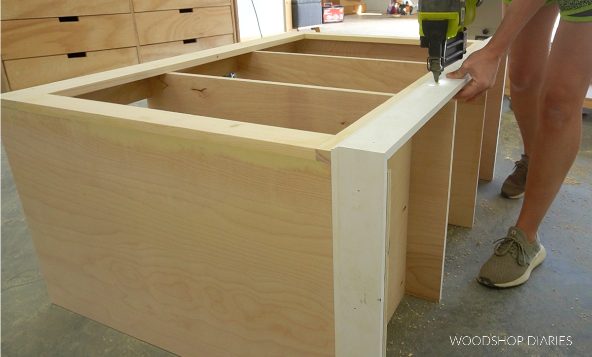 Shara Woodshop Diaries nailing baseboard trim along front bottom edge of cabinet