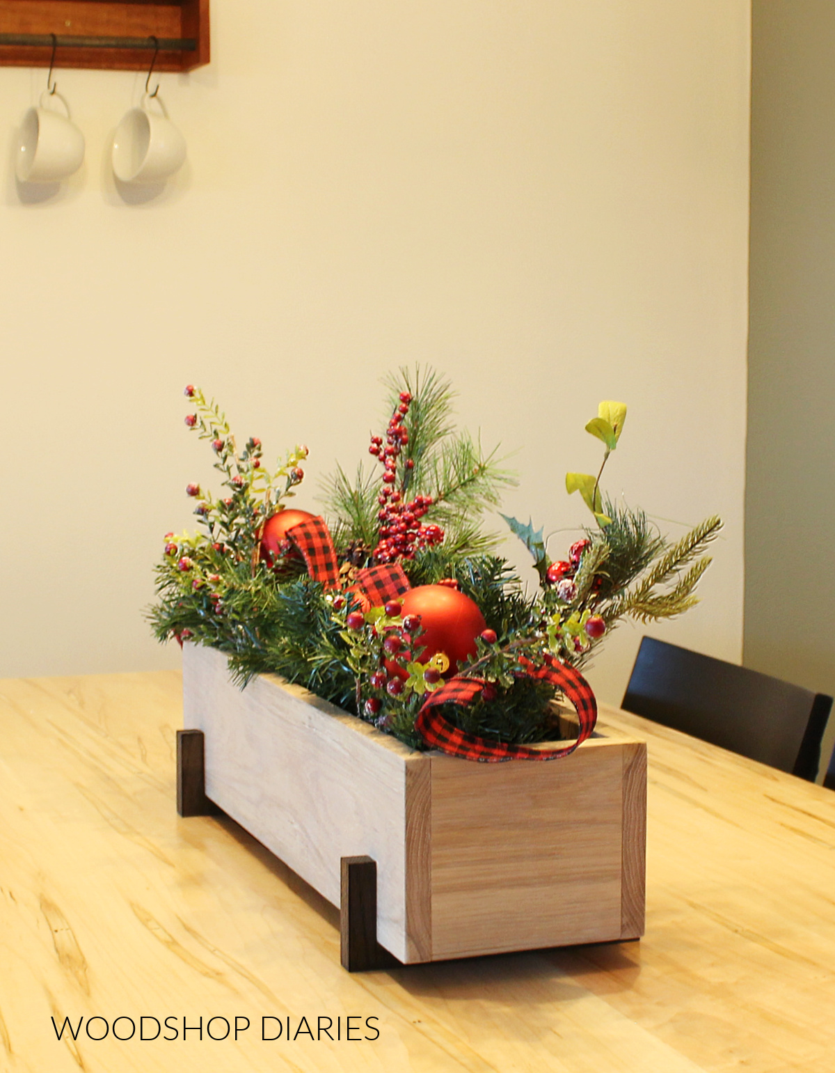 DIY wooden centerpiece box on dining table full of garland, ribbon, and ornaments