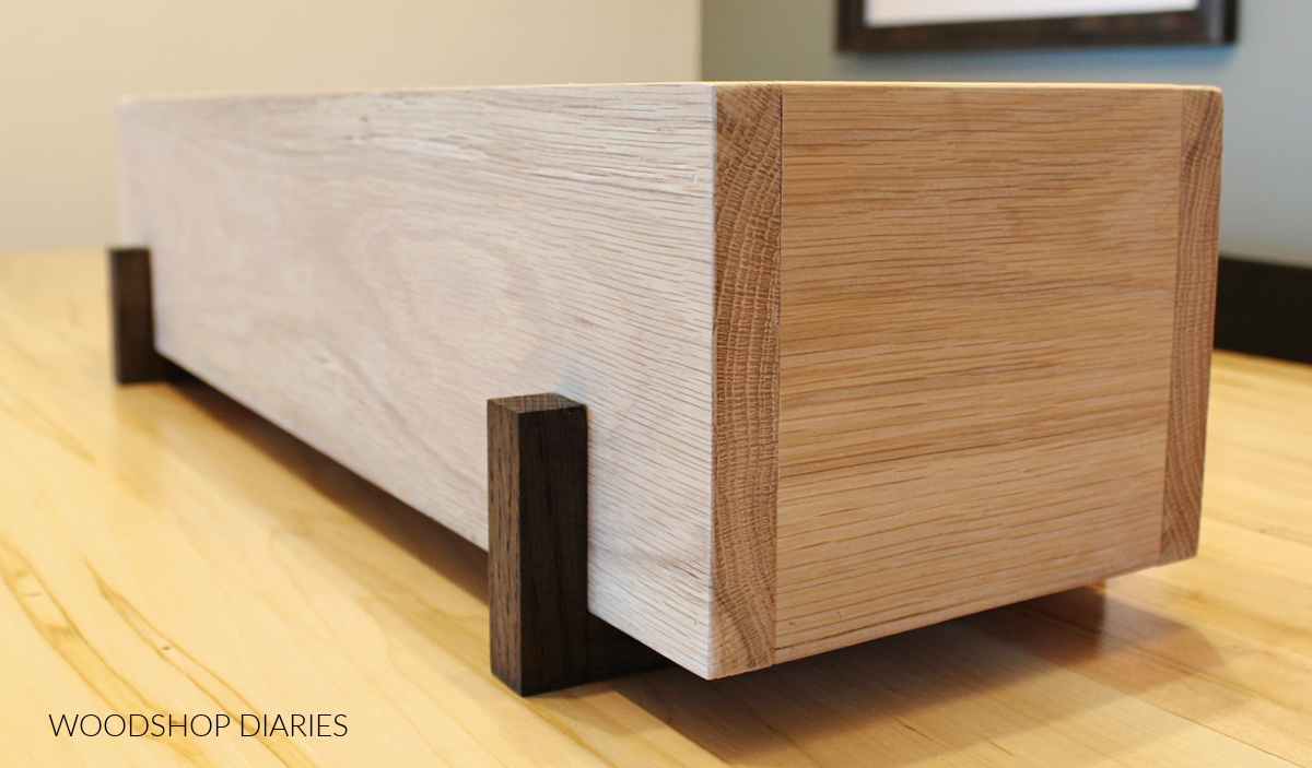 Close up of ¾" square dowel risers underneath white oak box