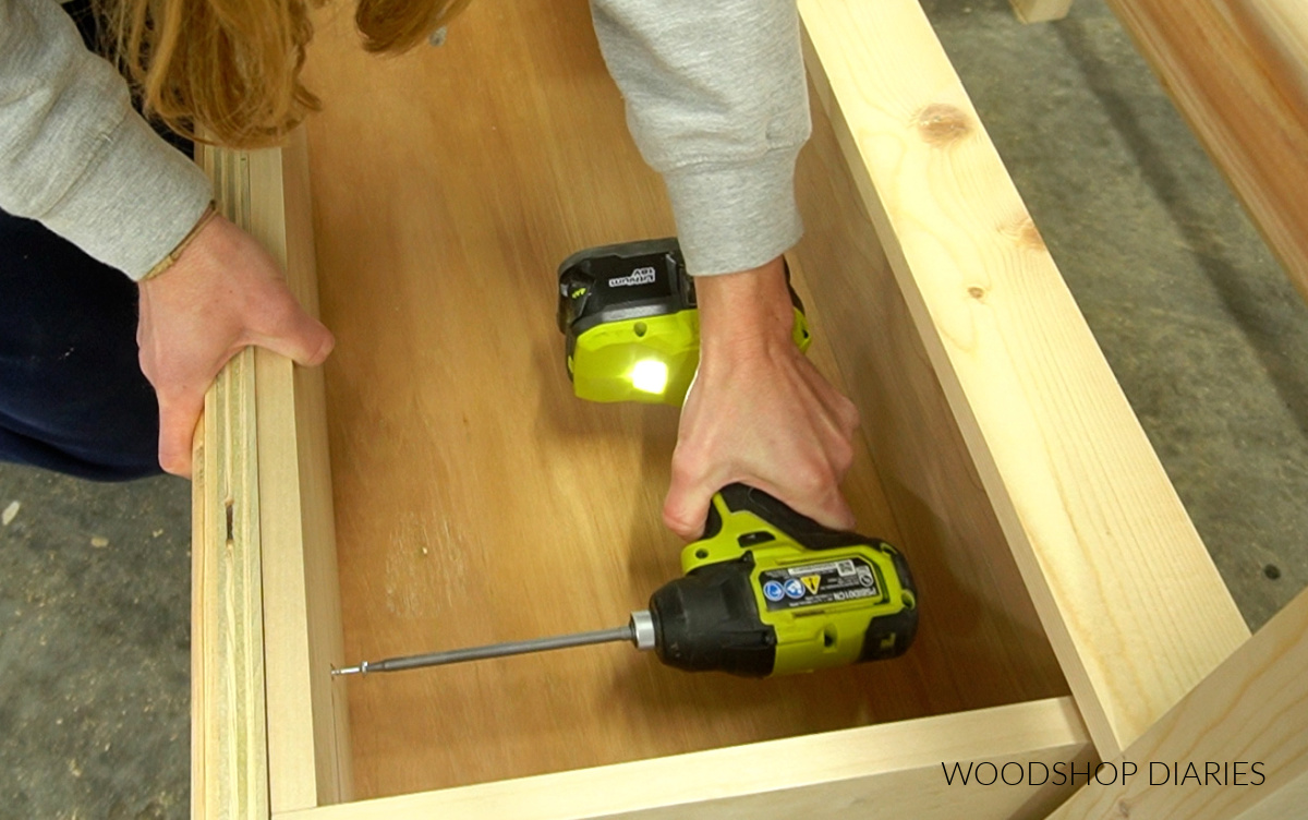 Close up of driving screws through inside of drawer box to attach plywood drawer fronts to DIY oversized nightstand