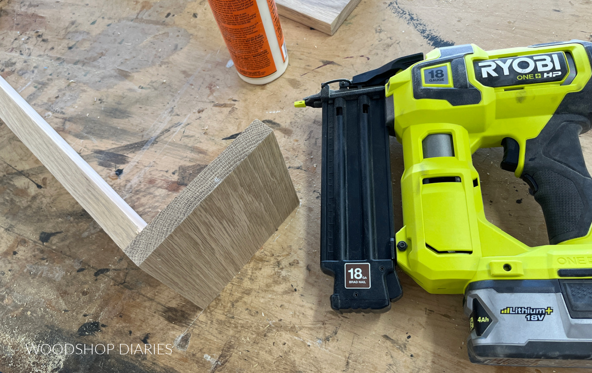 Brad nailer sitting next to partially assembled DIY wooden box on workbench