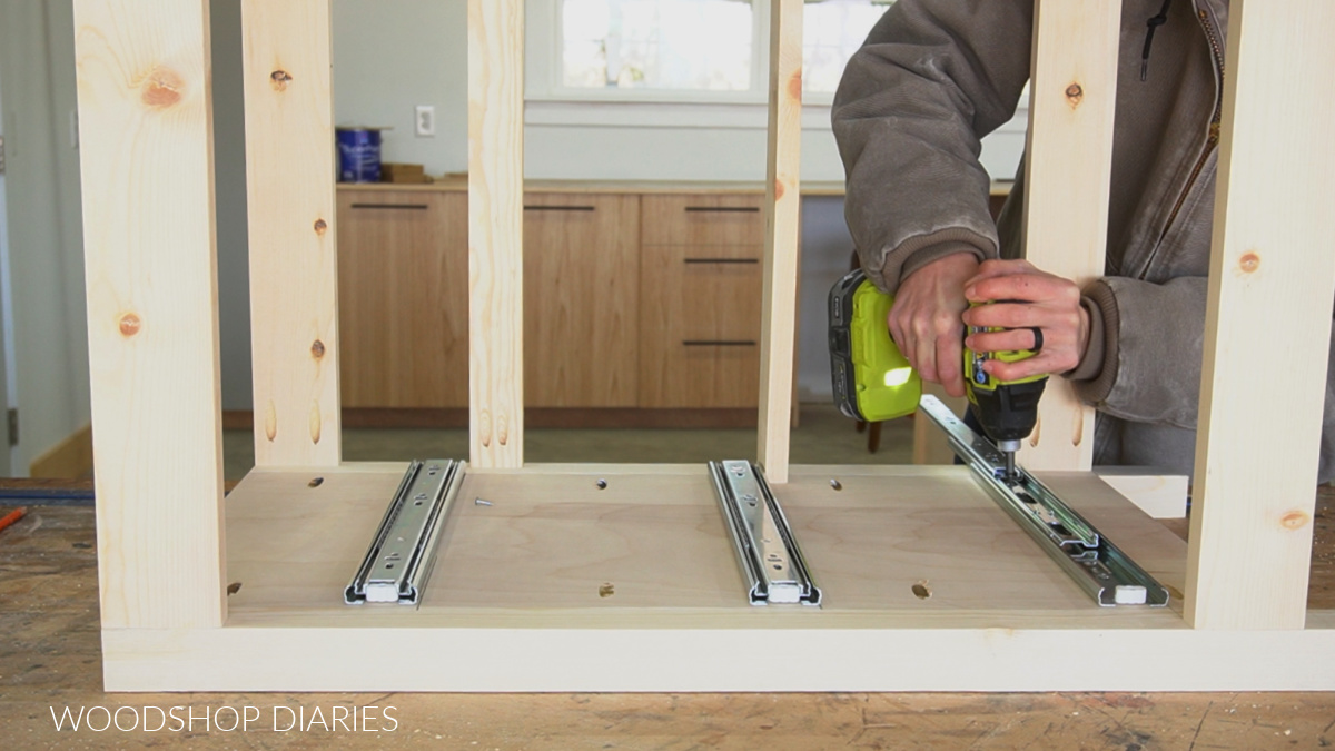 Shara Woodshop Diaries installing drawer slides into cabinet laid on its side on workbench