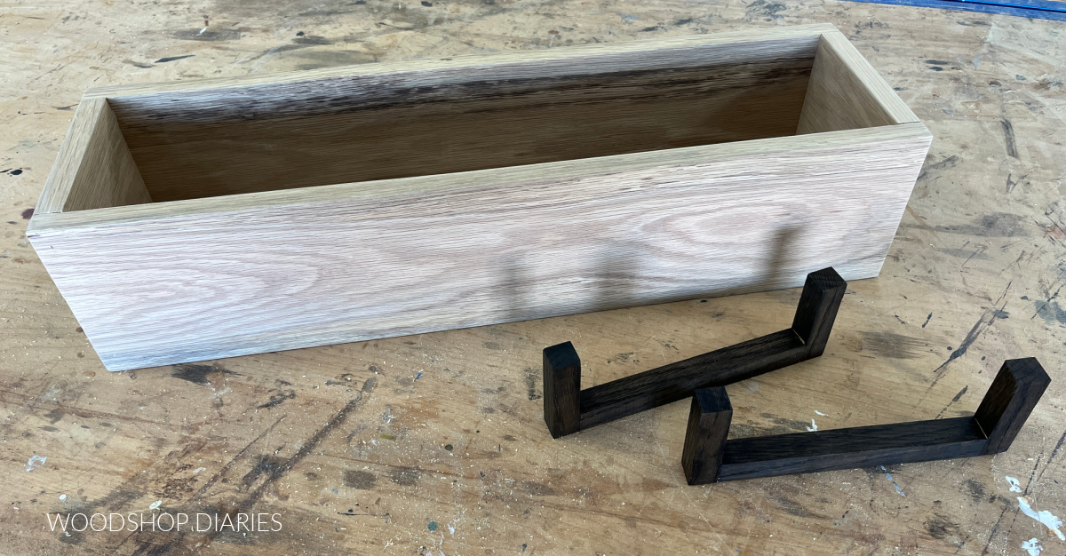 unfinished White oak box on workbench with black stained risers