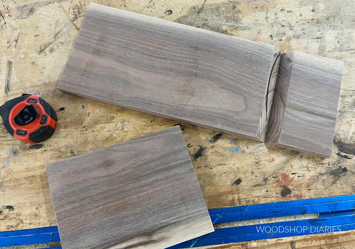 Walnut pieces cut to size from cut list lying on work surface with tape measure