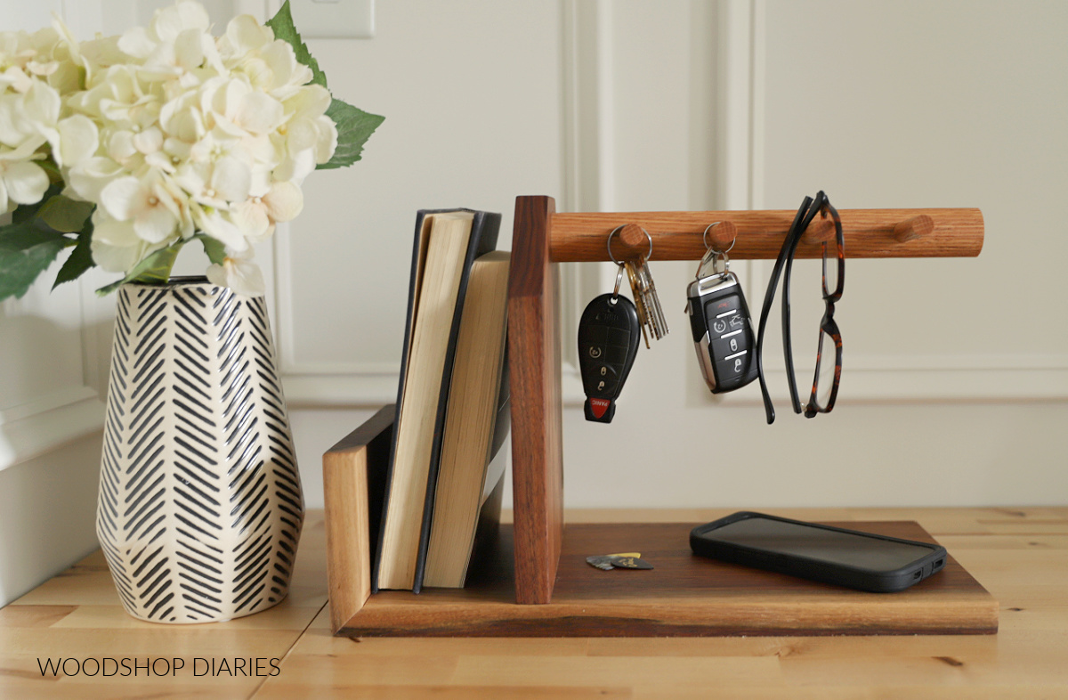 Completed DIY scrap wood catch all tray with key holder--keys and glasses hanging from pegs with books in side section