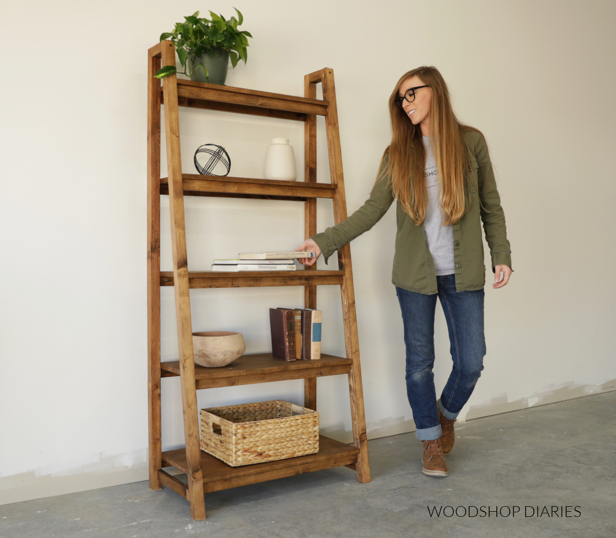 Shara Woodshop Diaries placing book onto DIY freestanding ladder bookshelf