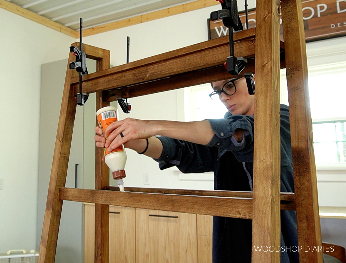 Shara Woodshop Diaries applying wood glue to shelf support rungs