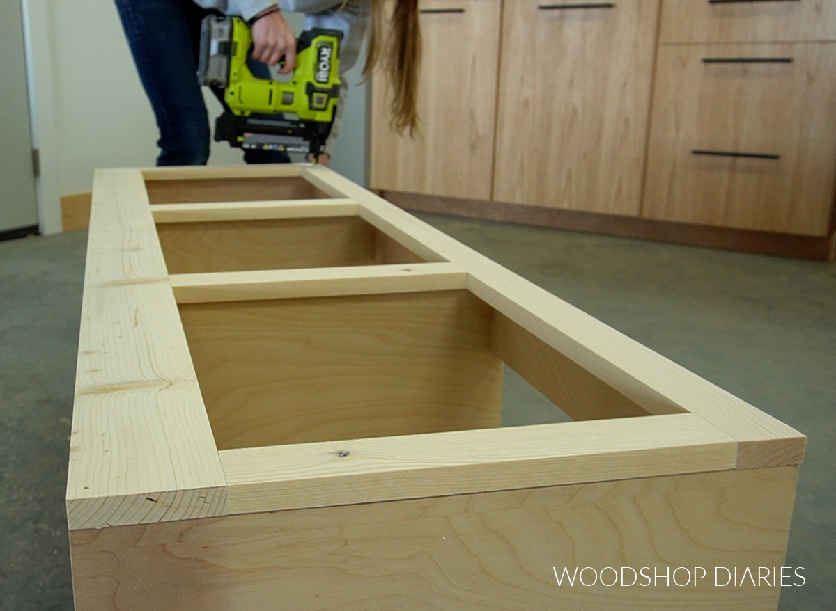 Shara Woodshop Diaries installing face frame onto front of storage bench with brad nailer