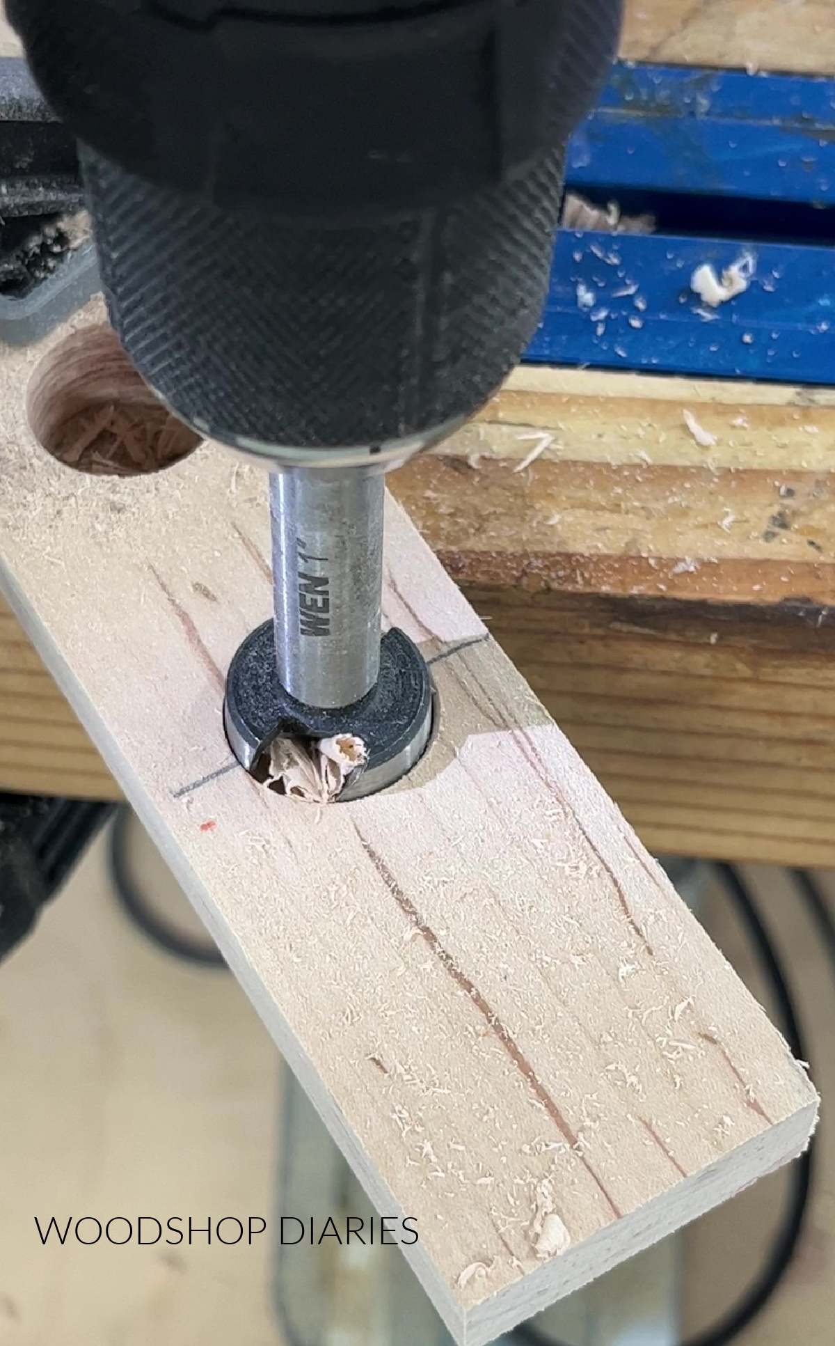 Close up of forstner bit drilling test tube holes in maple board