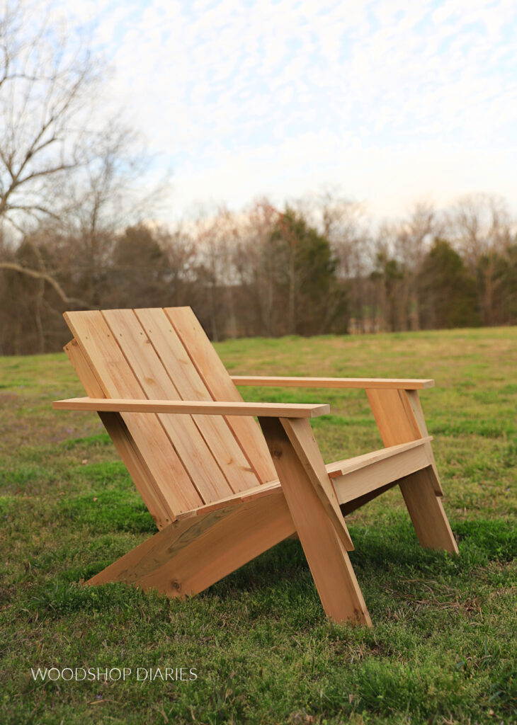Modern cedar DIY Adirondack chair sitting in grass in front of tree line