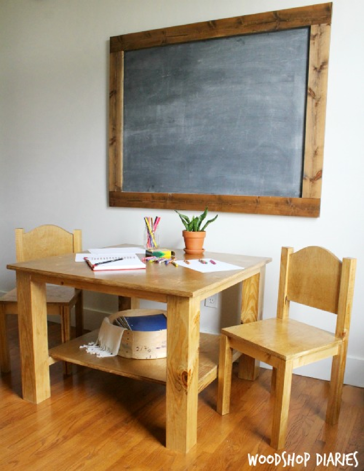 Wooden kids table with two chairs play set with chalkboard on wall
