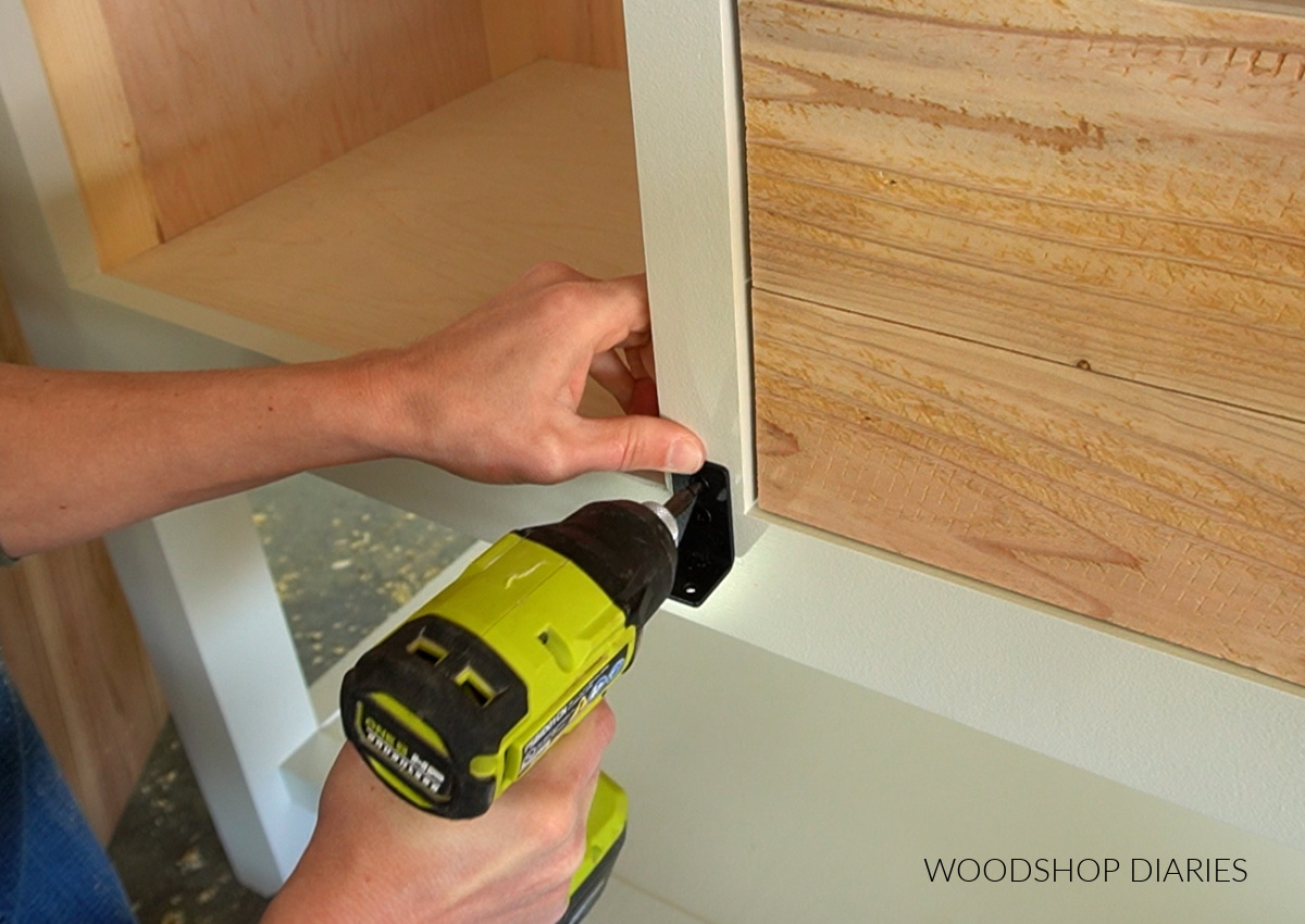 Using a drill to install bottom piece of sliding door hardware to run underneath door