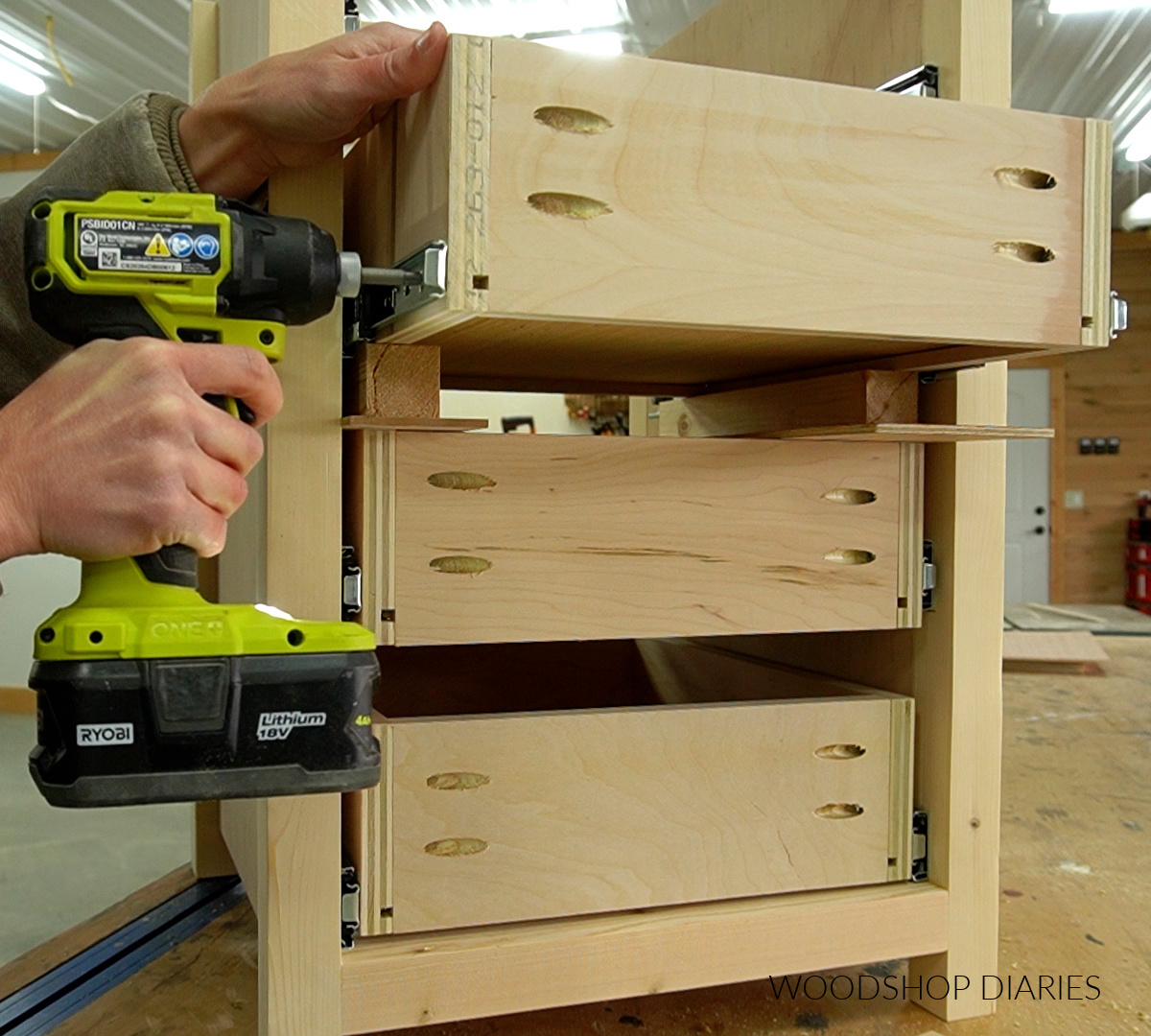 Close up using driver to drive screws through drawer slide into side of drawer box in end table cabinet