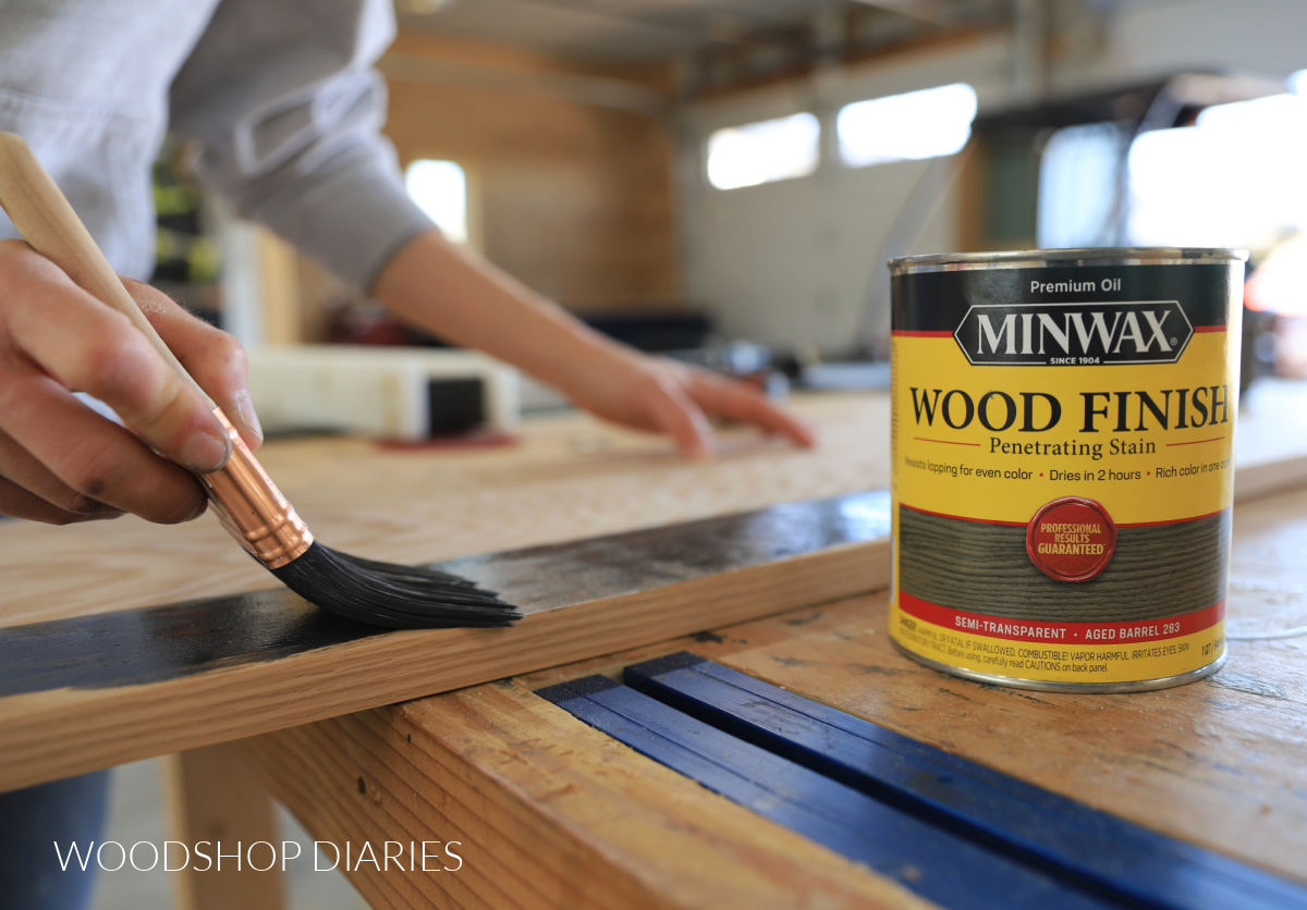 Close up of minwax stain can and brush applying stain to red oak plywood