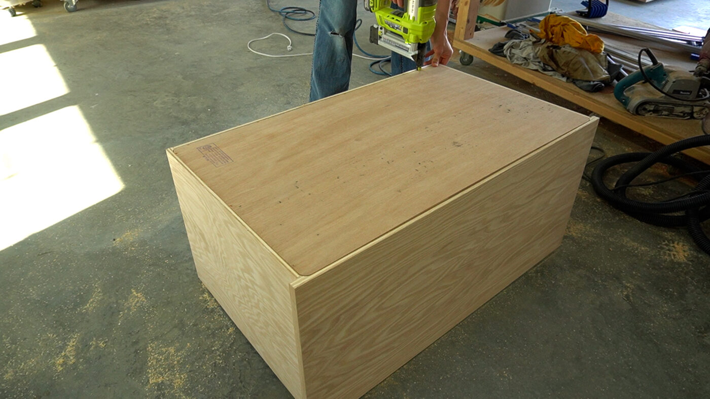 Shara Woodshop Diaries stapling back panel onto console cabinet