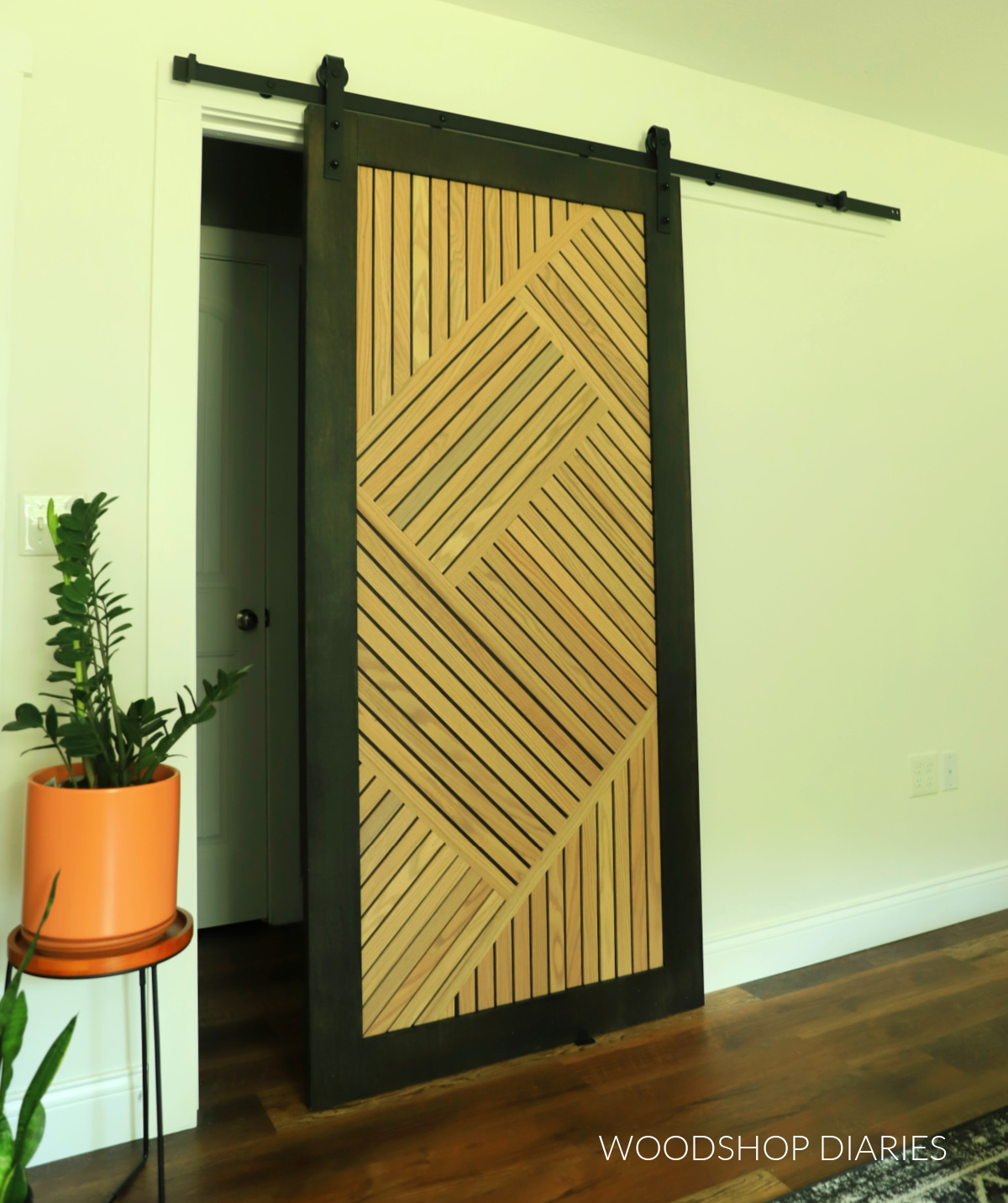 Modern geometric sliding door with wood slat design on white wall