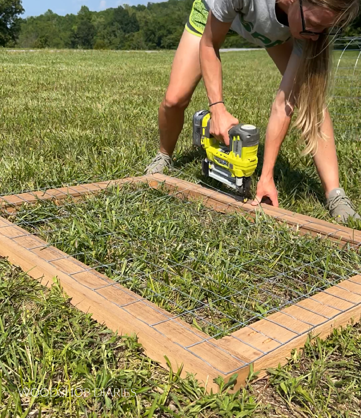 Shara stapling welded wire panel onto back side of gate frame on grass