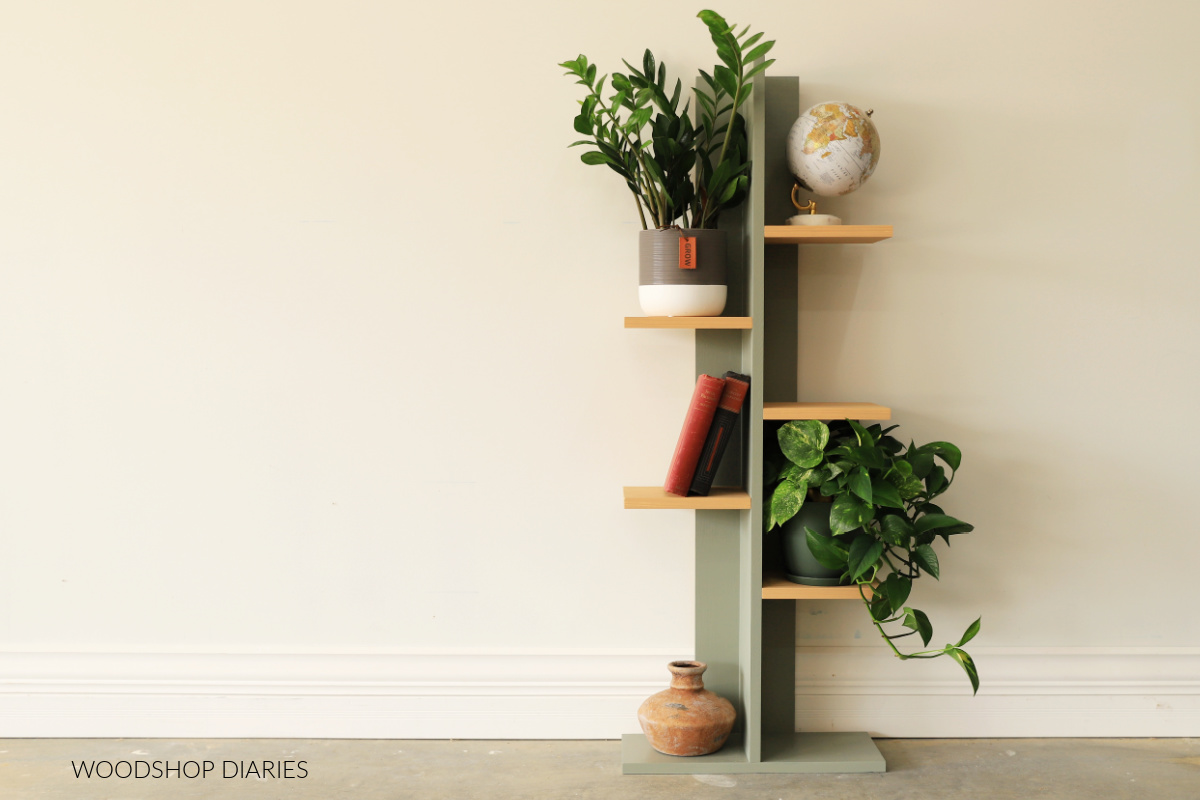 Vertical DIY plant shelf painted green with 5 tiered wooden shelves--3 on right and 2 on left