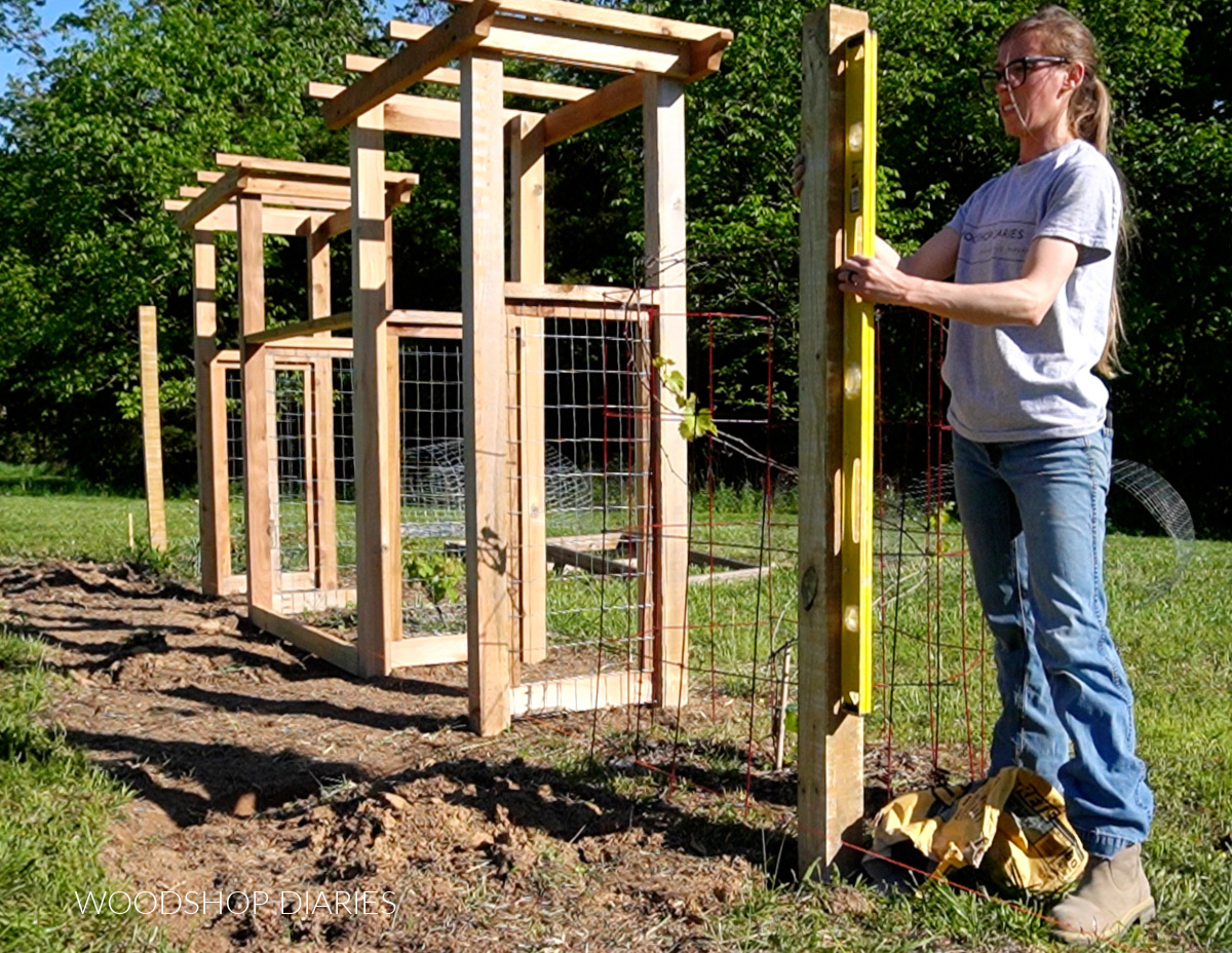 Shara Woodshop Diaries checking plumb on garden fence post