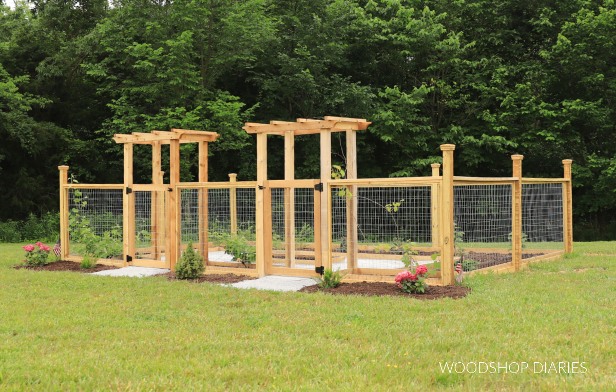 Enclosed garden with two arbors with gates. Gravel in middle and garden beds around fencing