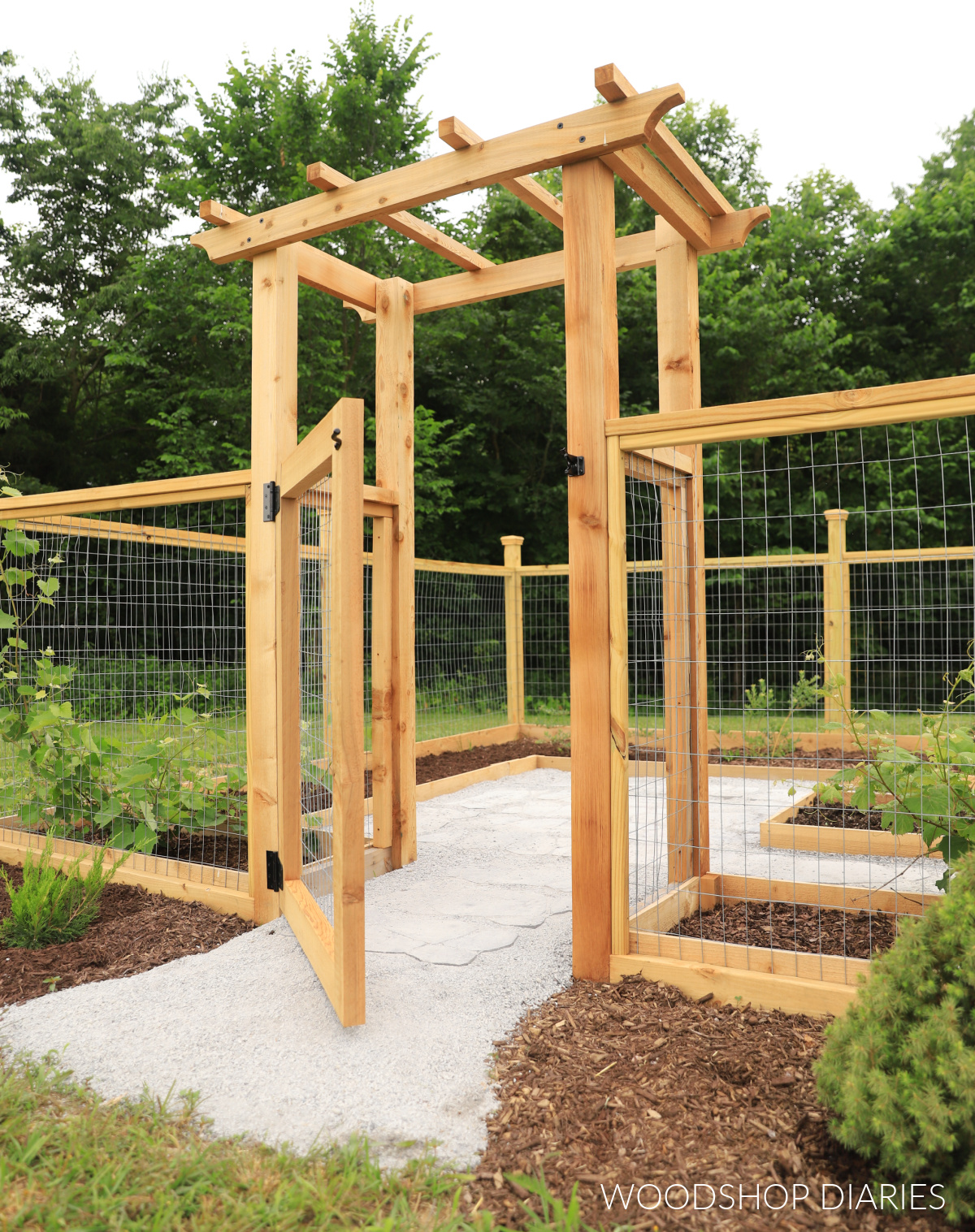 Cedar arbor with fencing and gate cracked open to reveal paver walkway inside garden