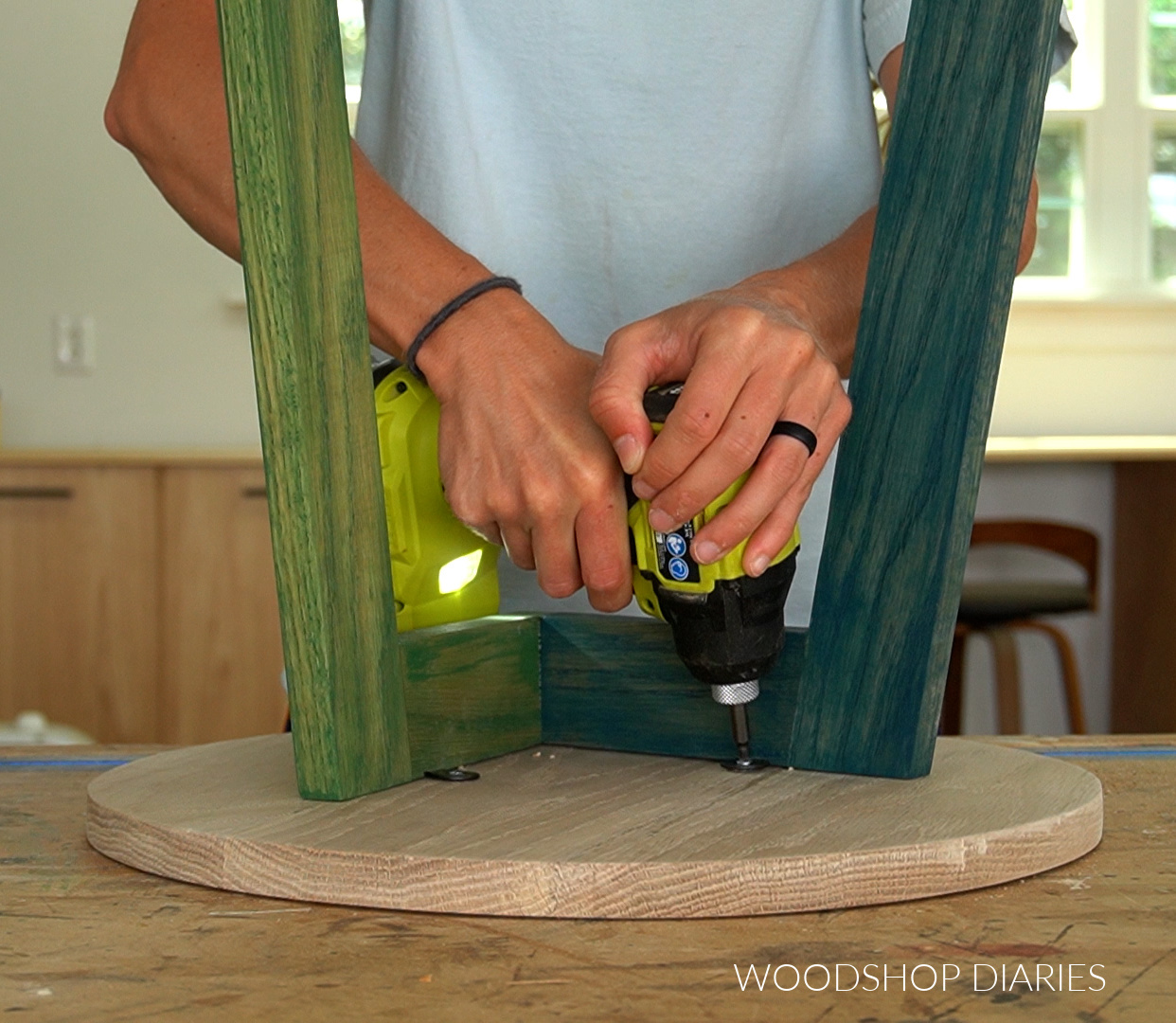 Close up of Shara Woodshop Diaries using screws to attach table to to C table base