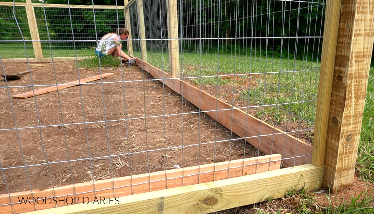 Shara Woodshop Diaries securing cedar fence pickets to bottom of fence framing on inside 