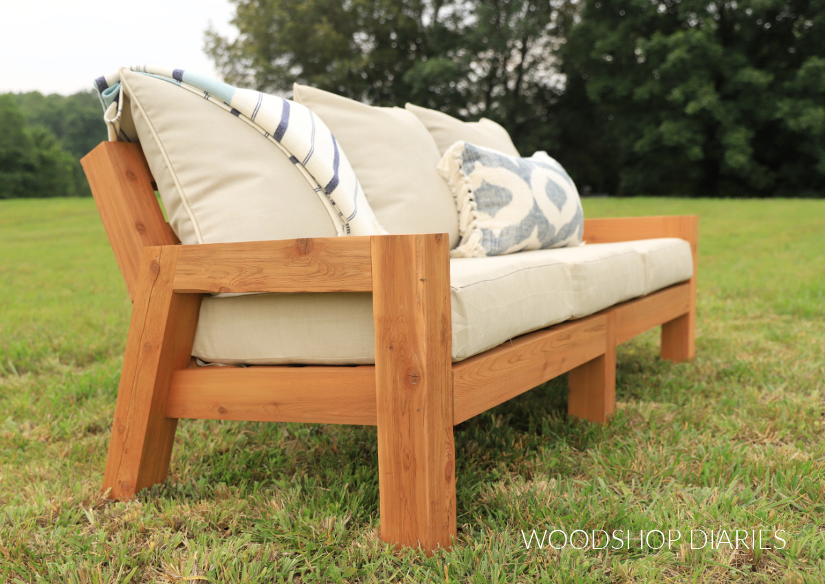 3 seater outdoor couch made with cedar wood sitting in yard with seat cushions