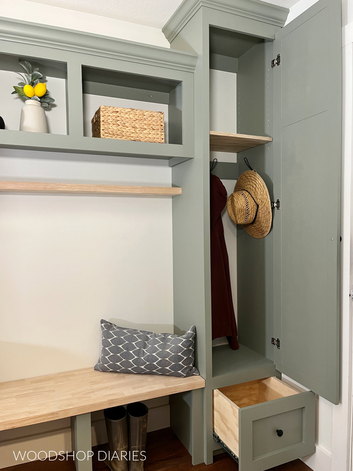 Close up of tall mudroom cabinet with door open revealing shelving and hanging hooks inside