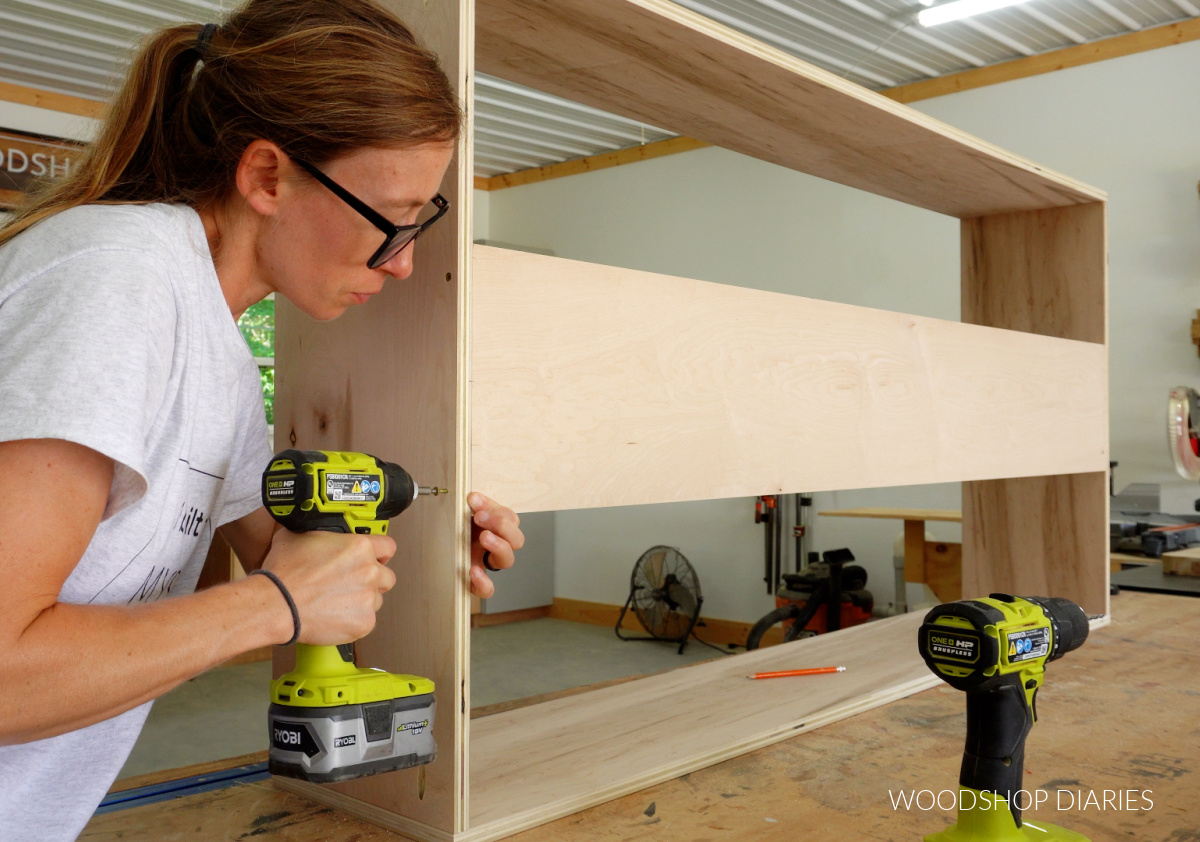Shara Woodshop Diaries securing back panel of plywood bookshelf using wood screws on workbench