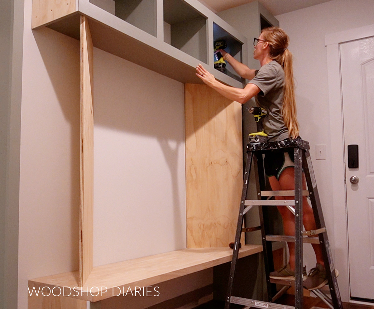 Shara Woodshop Diaries securing middle cubby cabinet to wall studs in hallway