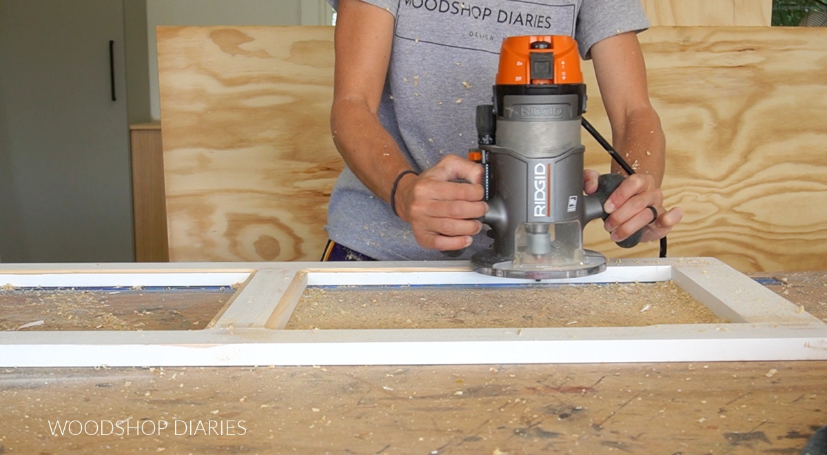Using router to cut rabbet in back side of cabinet door on workbench