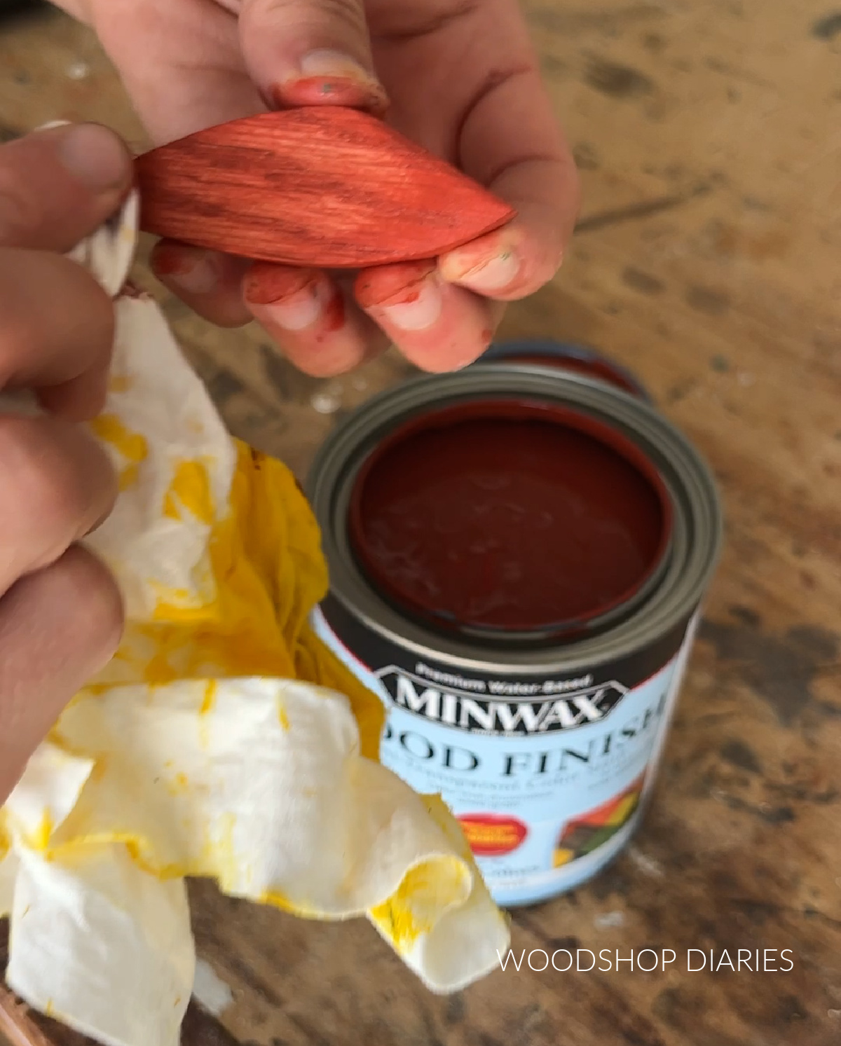 Applying red wood stain to wooden flower petal with rag