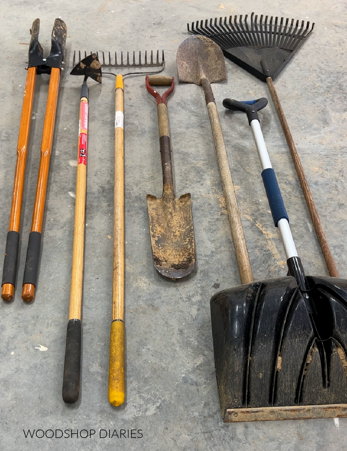 shovels, rakes and yard tools laid out on concrete floor