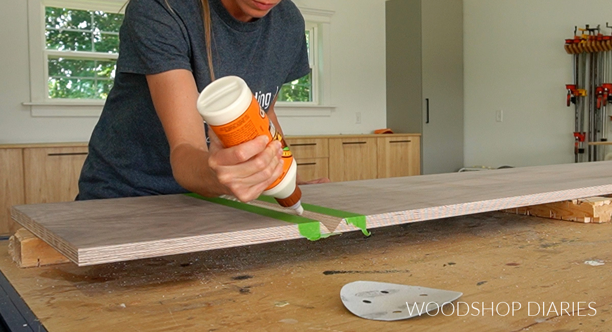 Applying wood glue to V joints of mitered corner console cabinet box