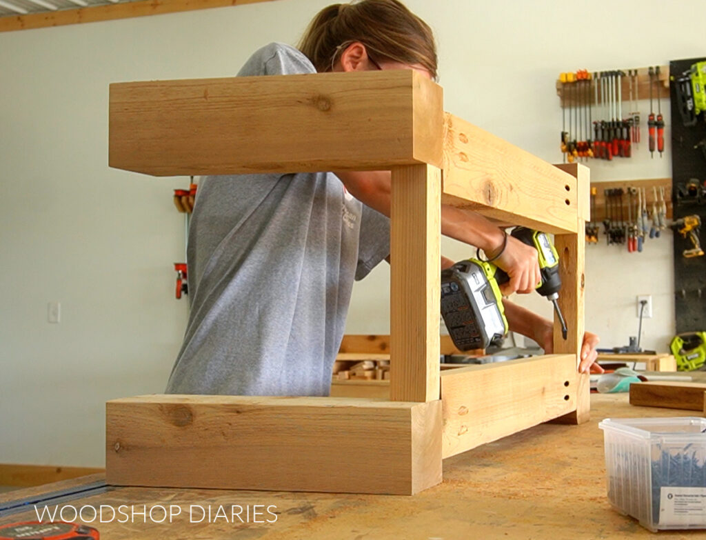 Shara Woodshop Diaries driving screws through side supports of outdoor coffee table base frame