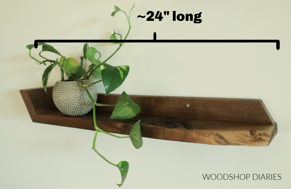 Walnut floating shelf hanging on wall with plant. Text and bracket showing length dimension of shelf to be about 24" long