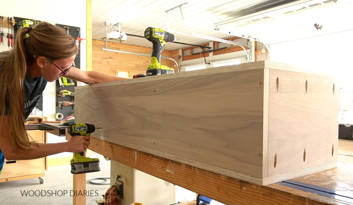 Shara Woodshop Diaries driving screws through back panel of cabinet box