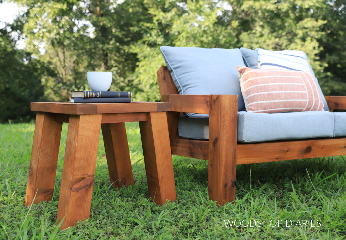 Outdoor side table sitting next to matching loveseat with angled legs made from 4x4s and 2x4s