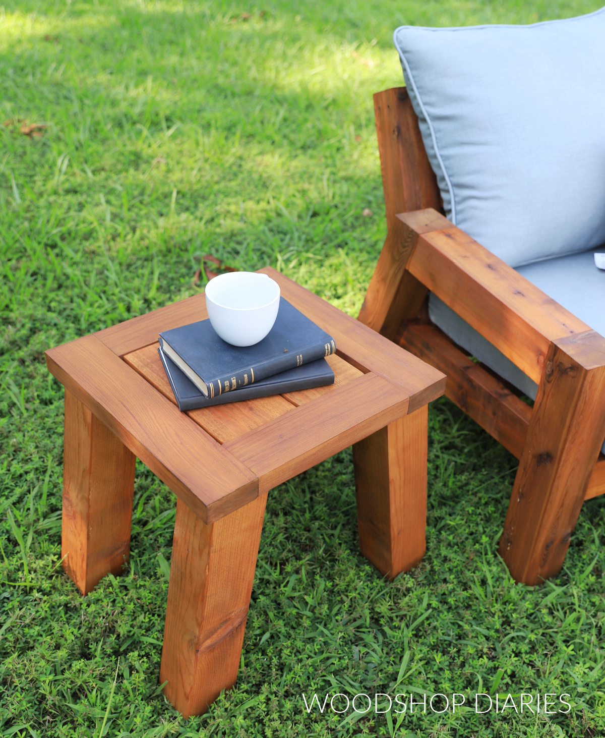Finished outdoor side table with chunky legs and Cabot Australian Timber Oil finish next to loveseat in grassy area