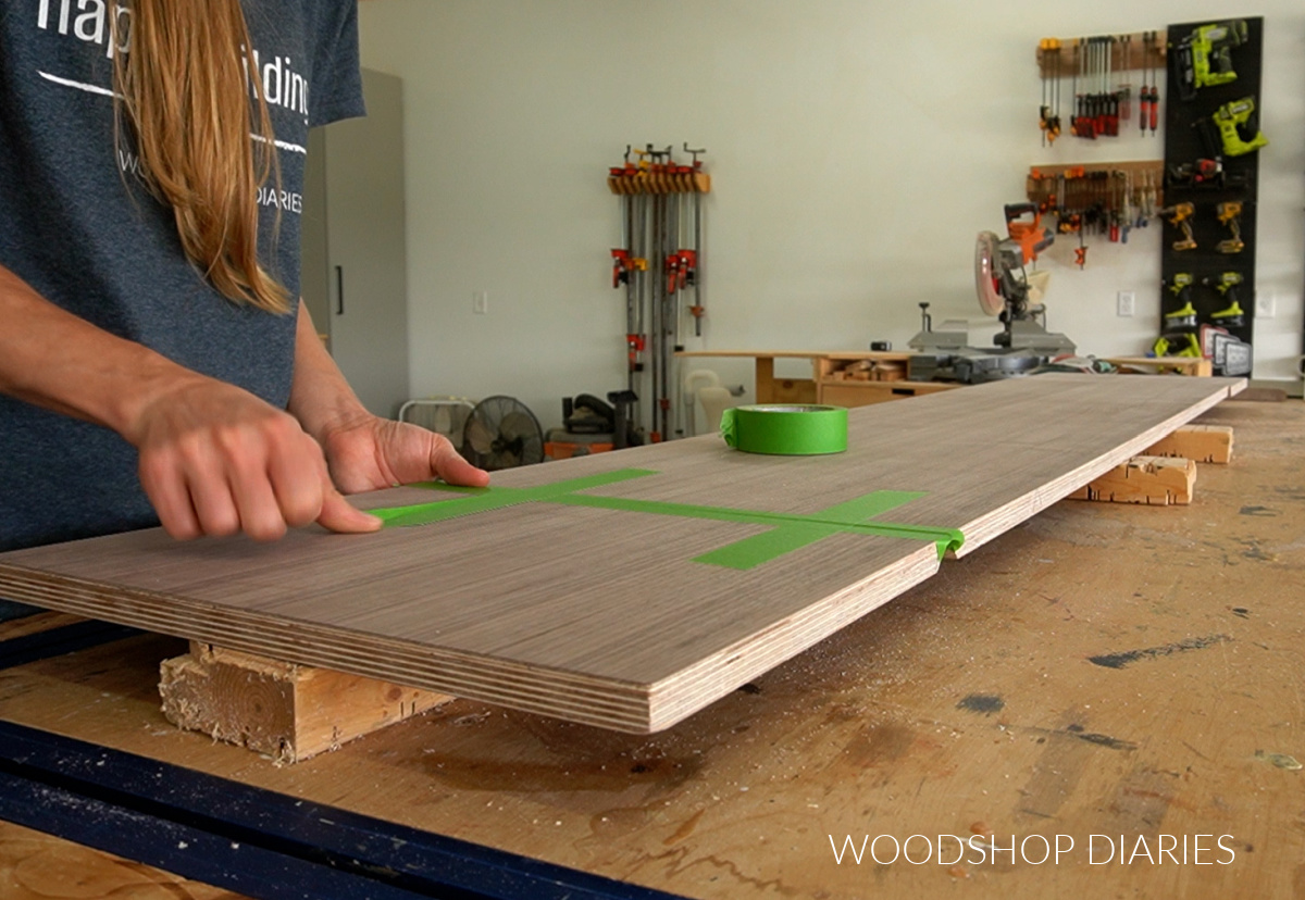 Applying painters tape to mitered joints on plywood panels on workbench