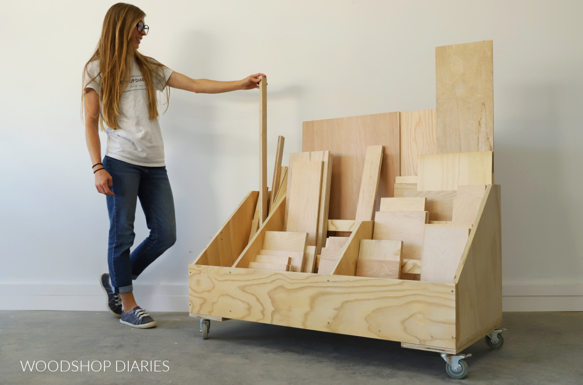 Shara Woodshop Diaries putting scrap plywood into scrap wood storage cart in workshop