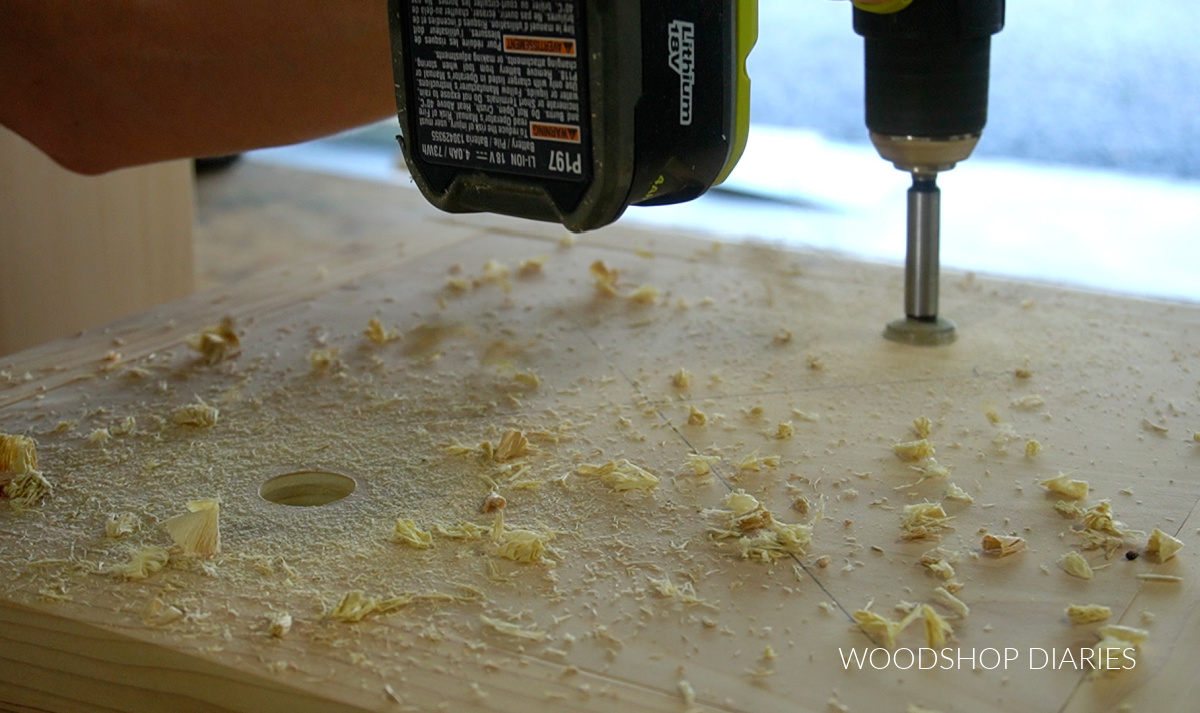 Using a drill and forstner bit to drill access holes in plywood center of base