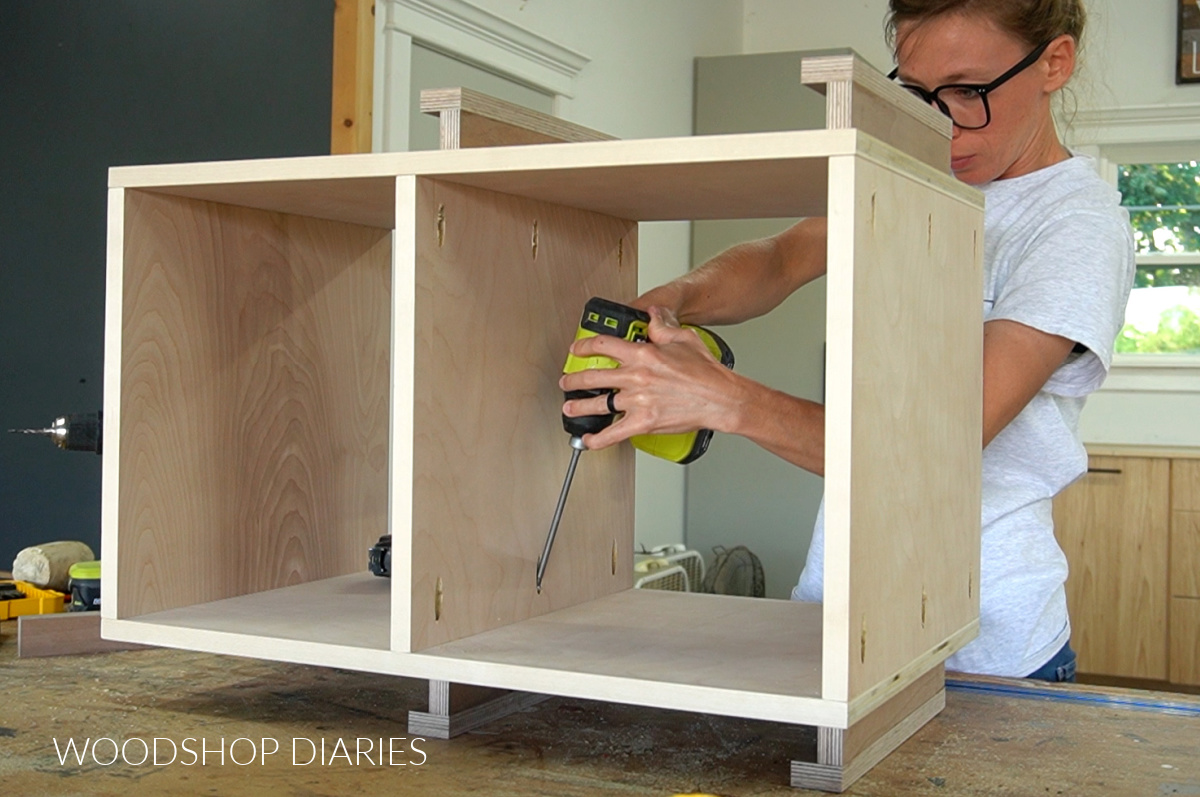 Shara Woodshop Diaries installing the middle shelf into the rotating bookshelf box