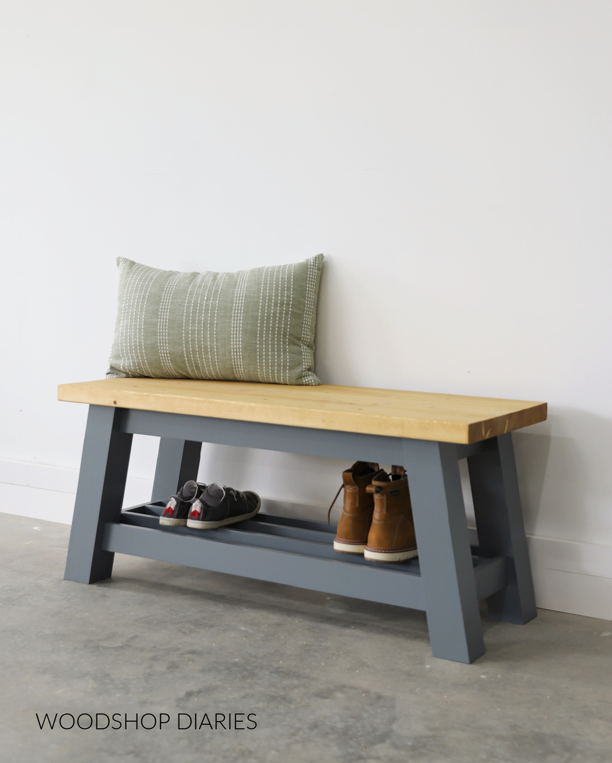 Completed DIY bench with shoe shelf against white wall--bottom of bench painted Behr Ocean Swell and top stained Minwax Golden Oak