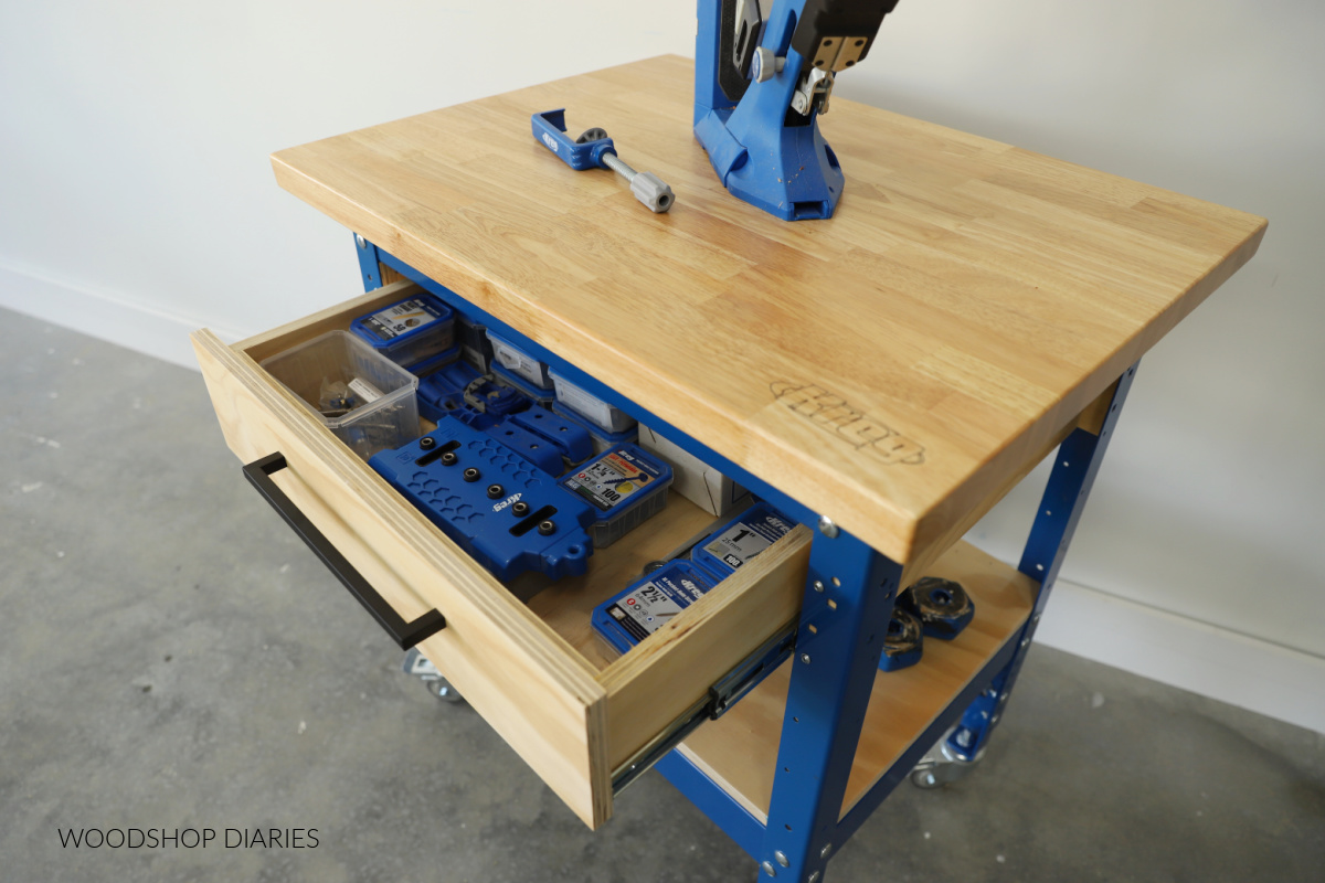 Top view of small shop workbench with drawer open showing screws and accessories inside