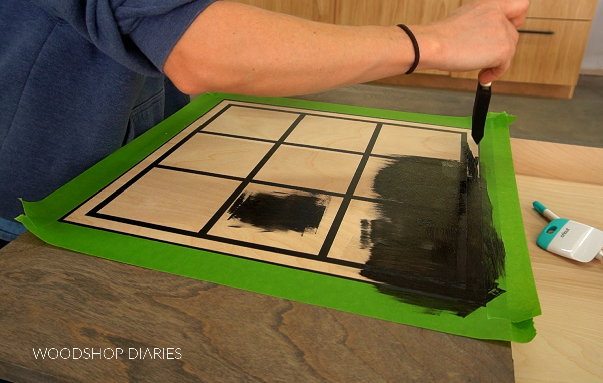 using a foam brush to stain tic tac toe game board onto table top
