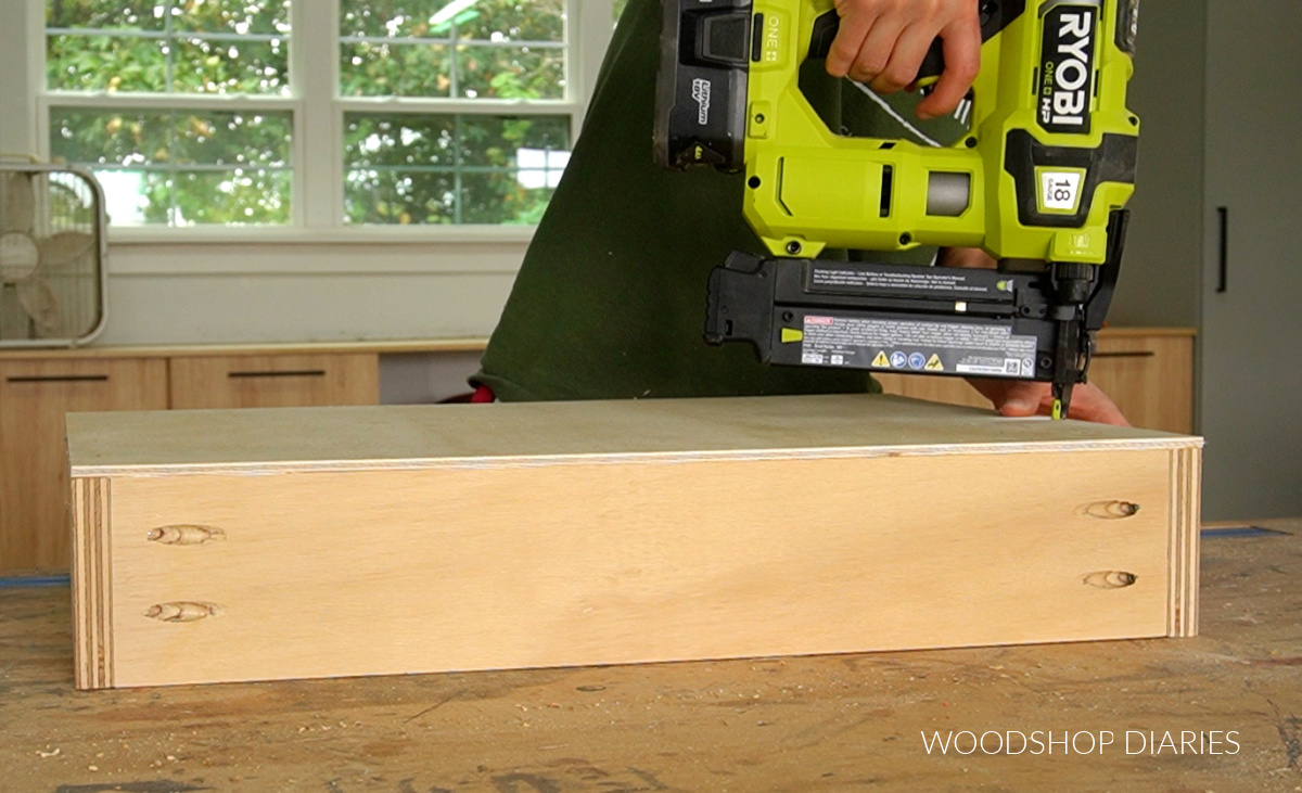 Shara Woodshop Diaries brad nailing plywood panel onto bottom of drawer box