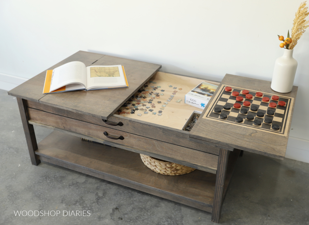 Coffee table with top flipped open to reveal a shallow compartment for puzzles inside. Flipped top section contains a built in checker board