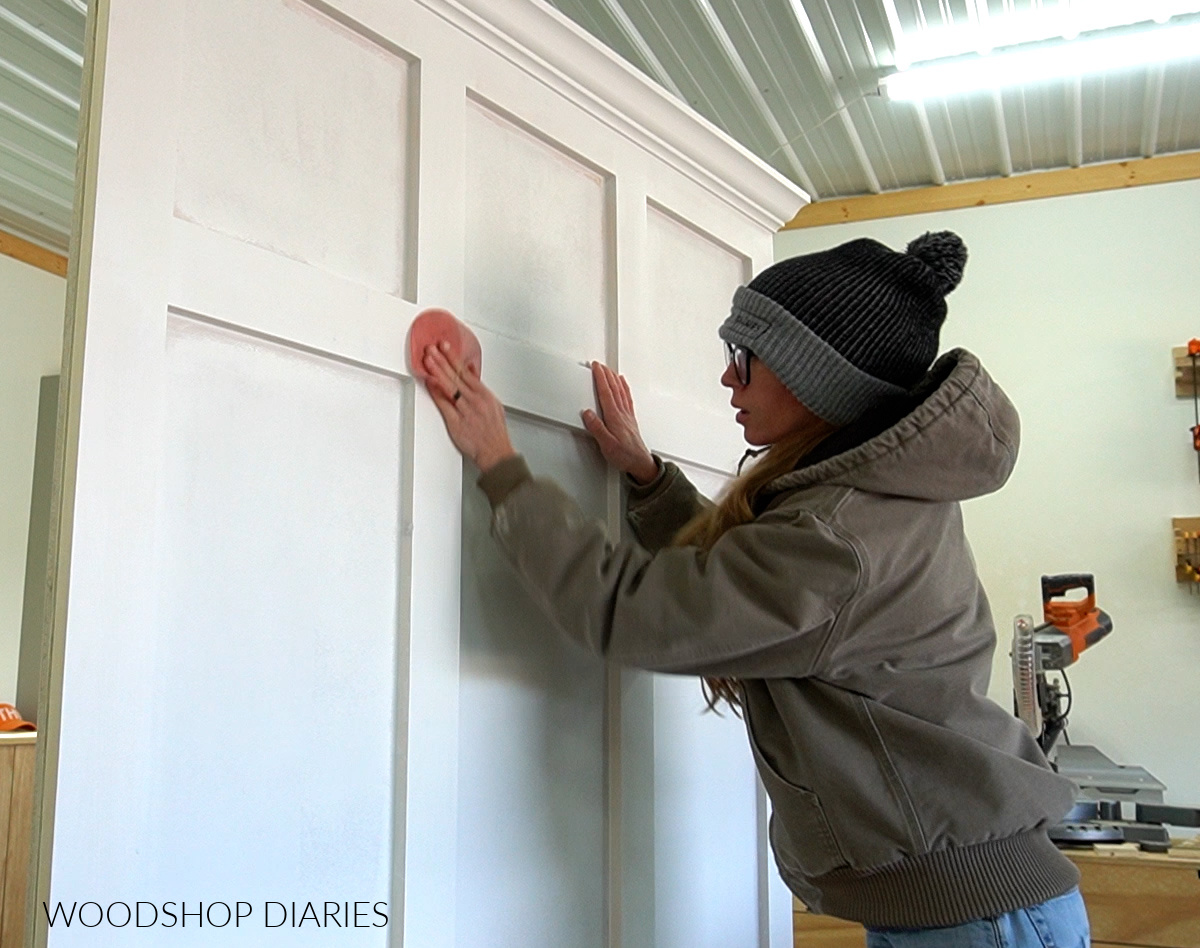 Shara Woodshop Diaries hand sanding primed hall tree piece in workshop before applying paint